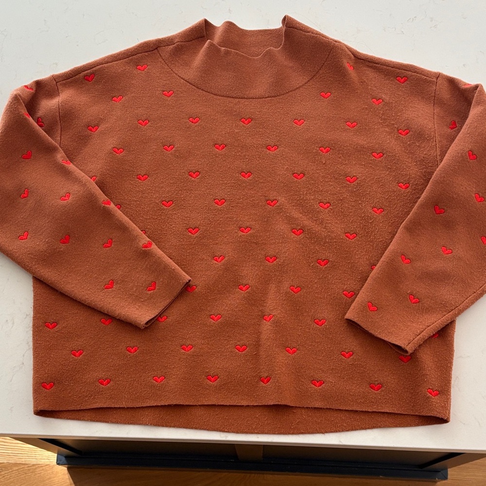Maeve Cary’s Mock-Neck Sweater with Red Heart Details